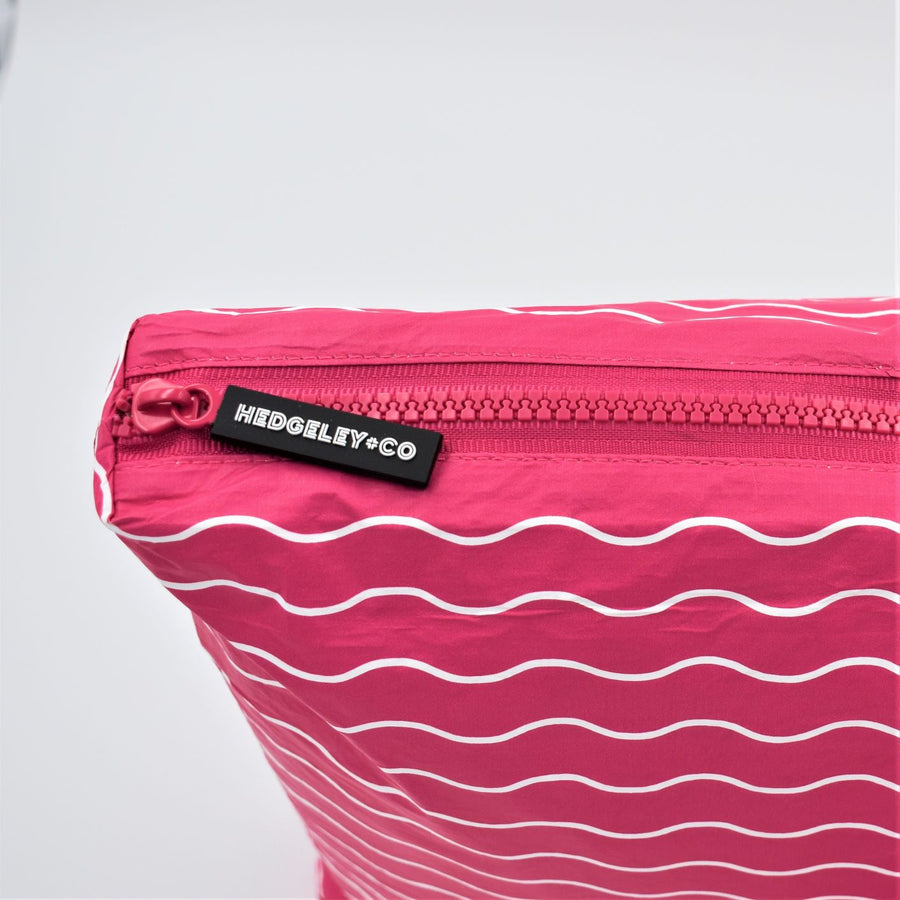 Zip detail of Mini zip pouch in Waving pattern in hot pink and white.