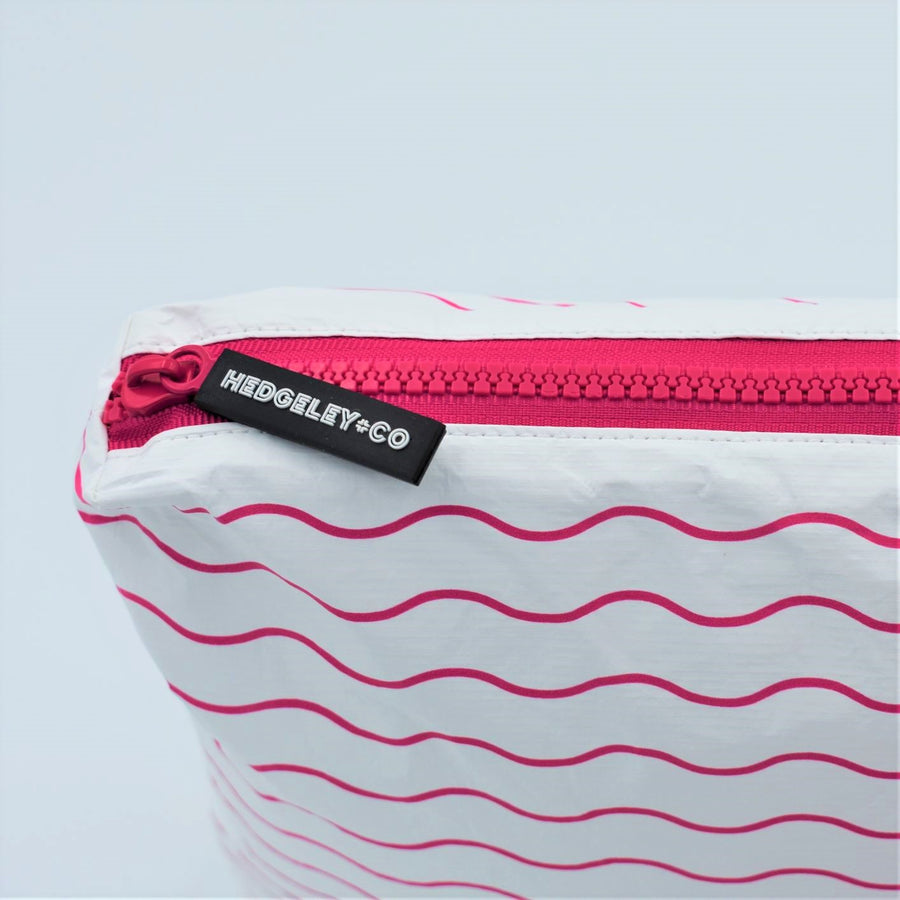 Zip detail of Small zip pouch in Waving pattern in hot pink and white.